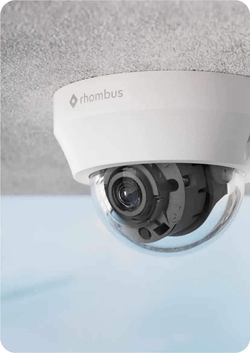 A sleek R230 Rhombus dome security camera is mounted on a grey ceiling, showcasing its versatile design for both indoor and outdoor security needs. This high-quality dome security camera features advanced motion detection and infrared night vision capabilities, ensuring optimal video quality and perimeter protection even in low light conditions.