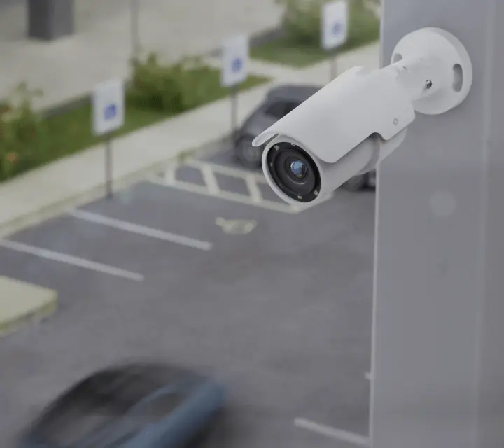 The R545 bullet surveillance camera, which has a wide angle lens compared to the R540, is mounted outside an office. It is known for long-range coverage and detailed image quality in outdoor settings.