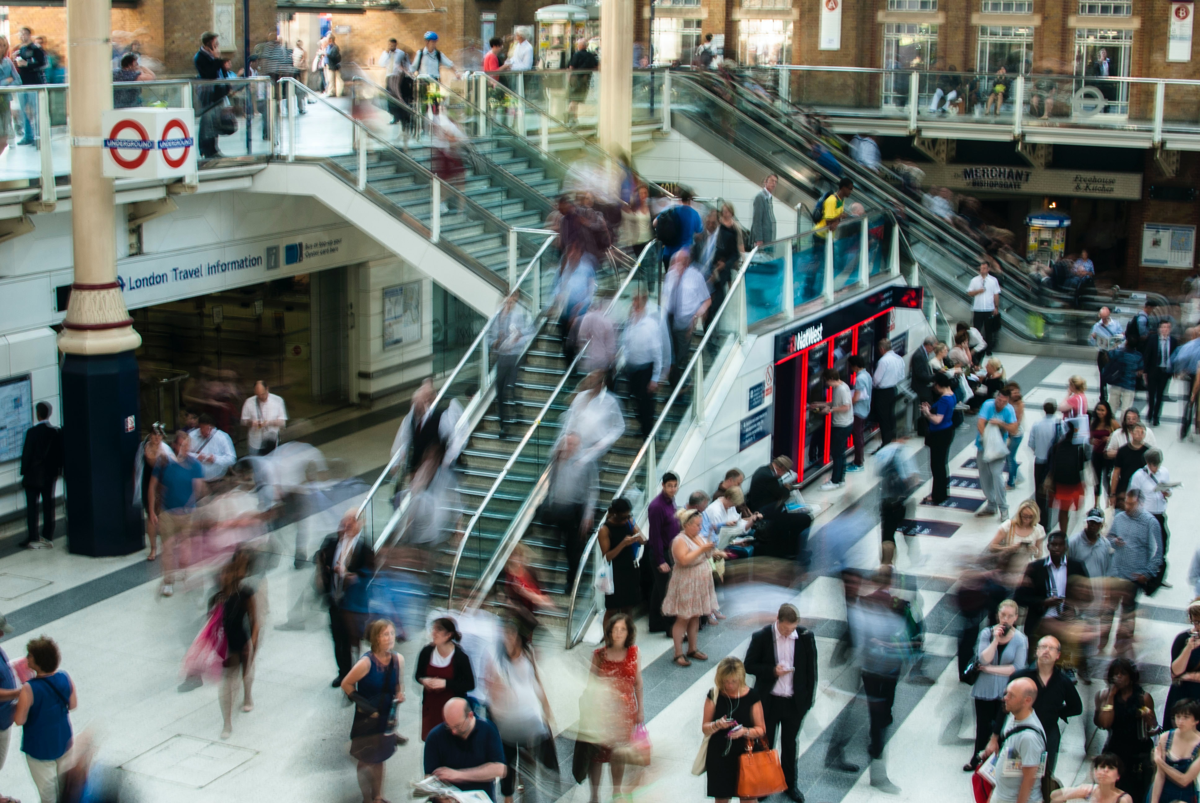 Time-lapse of busy mall showing blurred pedestrians using escalators and stairs.