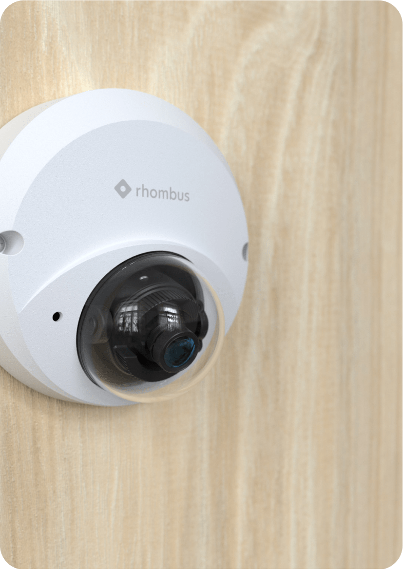 Rhombus R170 Micro-Dome Camera installed on a wooden wall, showcasing its sleek form factor and versatility for indoor settings. This standard dome security camera features a discreet design, making it ideal for retail stores and other security systems that require unobtrusive monitoring. The R170 offers high-quality images and video quality, with motion detection capabilities.